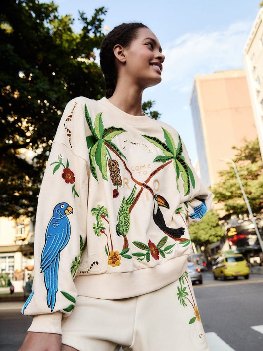 Beige sweatshirt with tropical designs including parrots, toucans, and palm trees