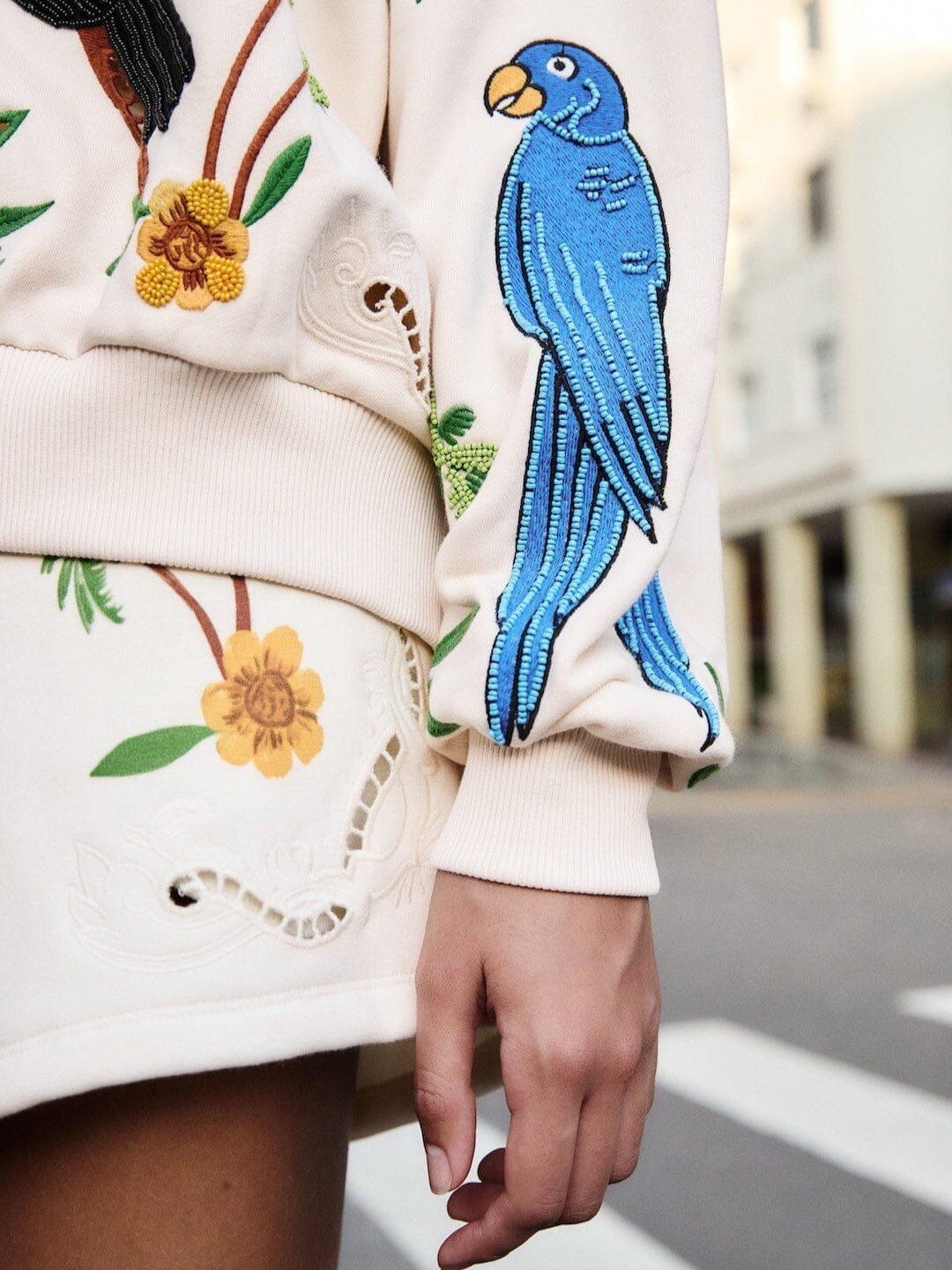 Beige sweatshirt with tropical designs including parrots, toucans, and palm trees