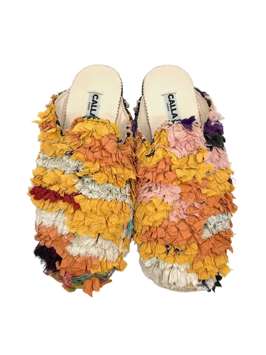A pair of open-toe mule slippers with thick, textured, frayed multicolor fabric uppers. The colors include yellow, orange, pink, white, and purple, with a cream-colored insole.