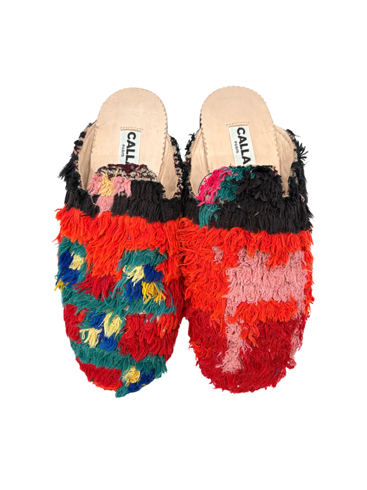 mule slippers featuring a vibrant, multicolored shaggy knit pattern on the uppers, a black fuzzy trim, and a light beige insole